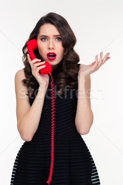 Stock photo: Shocked astonished beautiful retro styled woman talking on red telephone