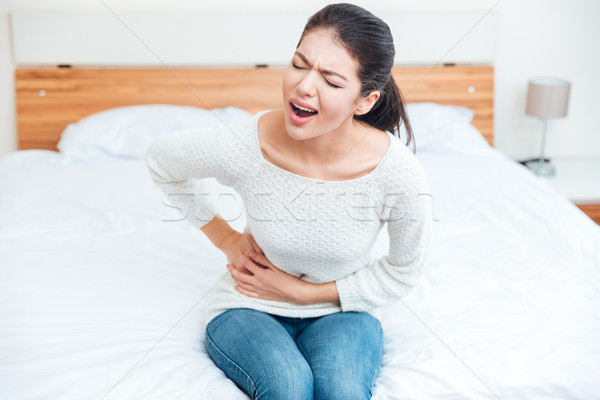 Nő megérint oldal fájdalom ül ágy Stock fotó © deandrobot