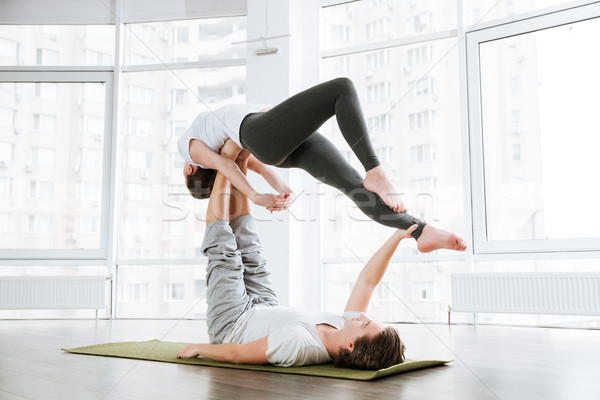 Couple practicing acro yoga on green mat in studio together Stock photo © deandrobot