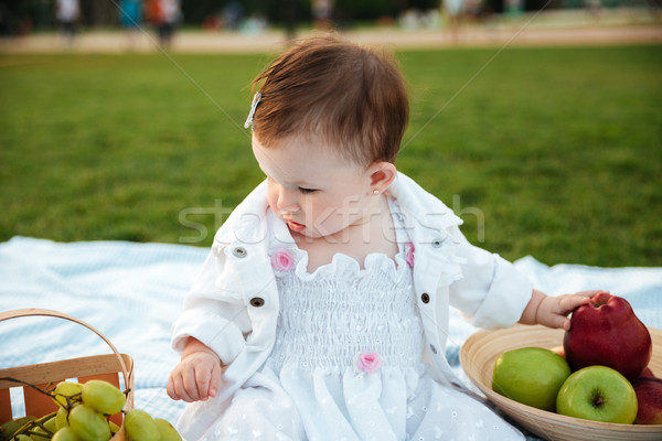 Cute little girl sitting and choosing fruits Stock photo © deandrobot