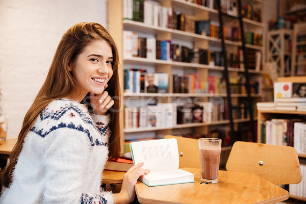 Girl sitting at the table and reading book in library Stock photo © deandrobot