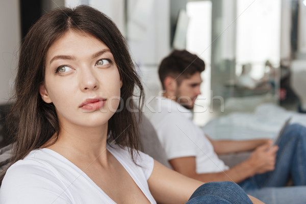 Sad woman sitting while her boyfriend using tablet at home Stock photo © deandrobot