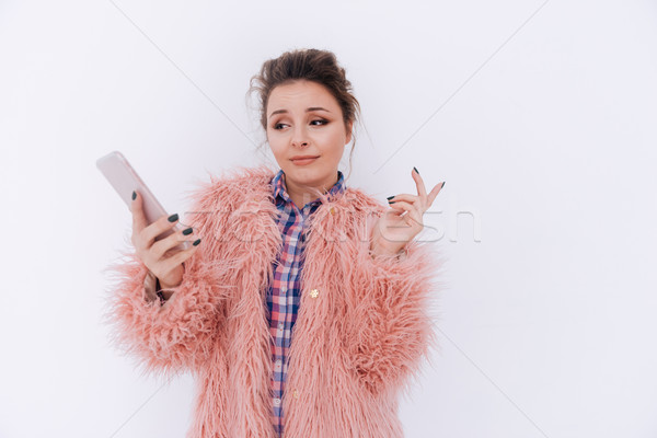 Surprised Woman in fur coat holding phone Stock photo © deandrobot