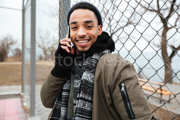 Foto stock: Sorridente · africano · homem · em · pé · falante · celular