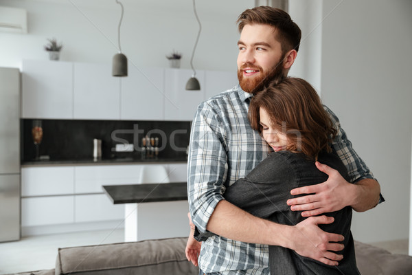 Cheerful loving couple standing in kitchen at home indoors Stock photo © deandrobot