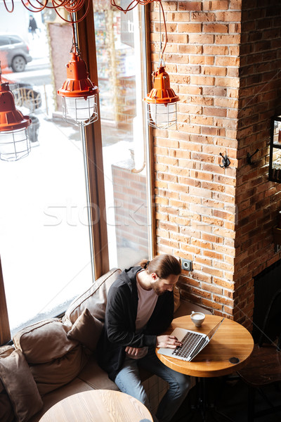 Dikey görüntü sakallı adam dizüstü bilgisayar kullanıyorsanız kafe Stok fotoğraf © deandrobot