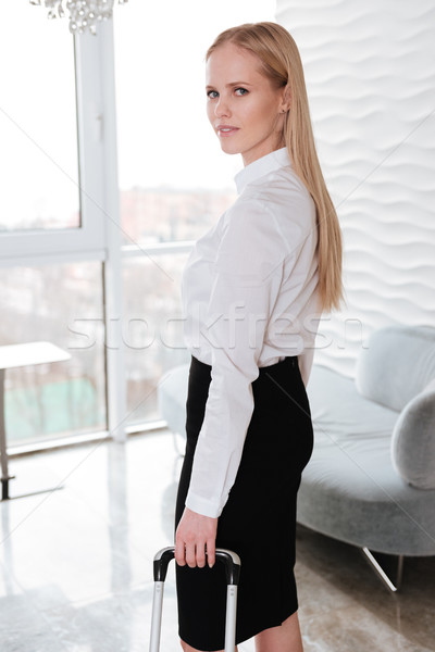 Pretty business woman standing in office holding suitcase. Stock photo © deandrobot