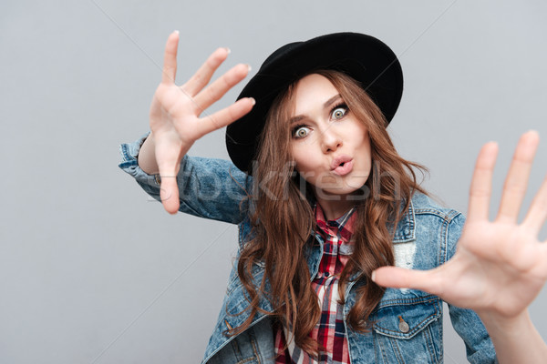 Girl in hat gesturing with hands and looking at camera Stock photo © deandrobot
