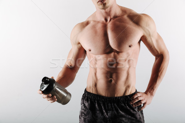 Cropped image of strong young sportsman holding bottle of water. Stock photo © deandrobot