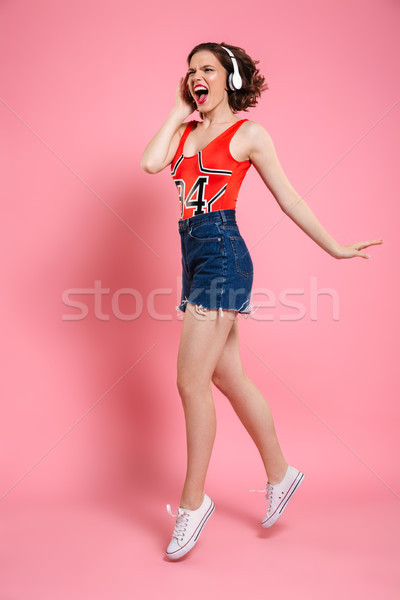 Gorgeous emotional young lady dancing and listening music. Stock photo © deandrobot