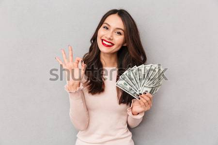 Image of lucky brunette female holding fan of 100 dollar bills b Stock photo © deandrobot