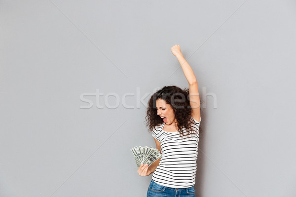 Emotional woman in striped t-shirt acting like winner holding fa Stock photo © deandrobot