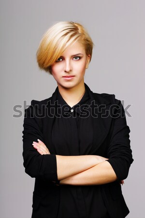 Confident beautiful young woman with arms folded on gray background Stock photo © deandrobot