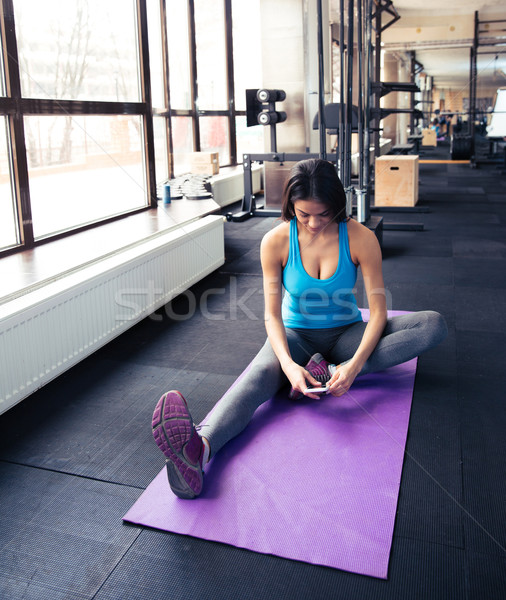Young woman sitting on the yoga mat and using smartphone Stock photo © deandrobot