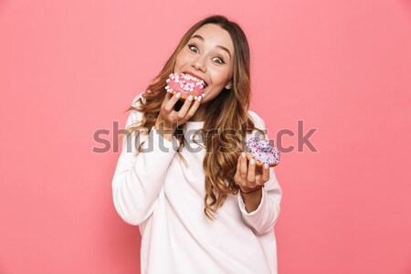 Fiatal nő eszik fánk rózsaszín arc háttér Stock fotó © deandrobot