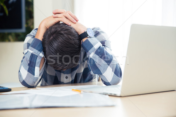 Worried man sitting at the table  Stock photo © deandrobot