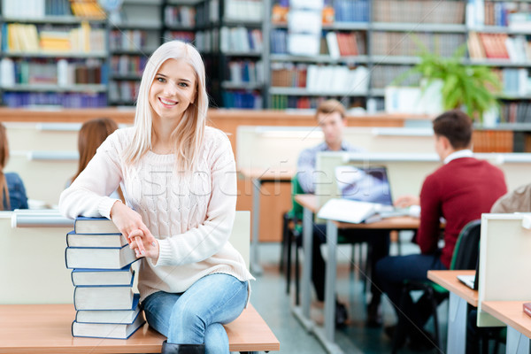 Female student sitting on the desk with books Stock photo © deandrobot