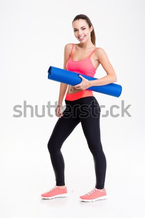 Attractive smiling young fitness woman holding yoga mat  Stock photo © deandrobot