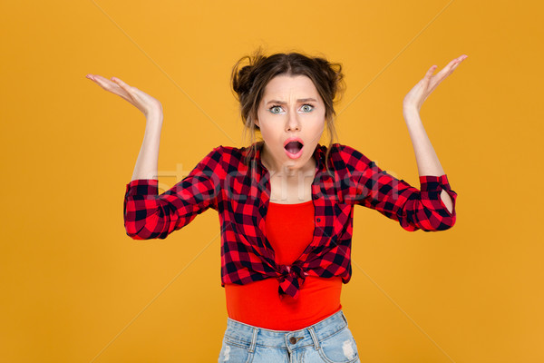 Shocked confused woman with raised hands holding copyspace on palms  Stock photo © deandrobot