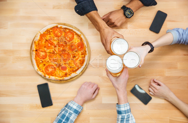 Multiethnic group of young people drinking beer and eating pizza  Stock photo © deandrobot