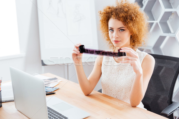 Pretty woman photographer looking through photographic film in office Stock photo © deandrobot