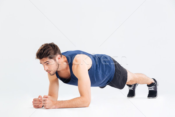 Focused handsome young sportsman doing plank core exercise Stock photo © deandrobot