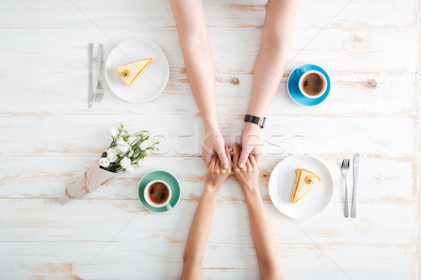 Top view of couple holding hands and eating dessert Stock photo © deandrobot