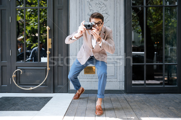 Cheerful funny photographer in round glasses taking pictures on street Stock photo © deandrobot