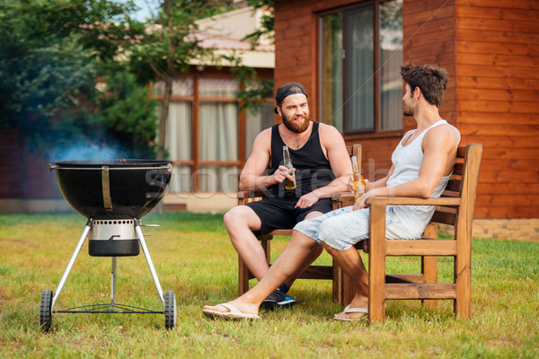 Two men sitting while preparing barbecue grill in park zone Stock photo © deandrobot