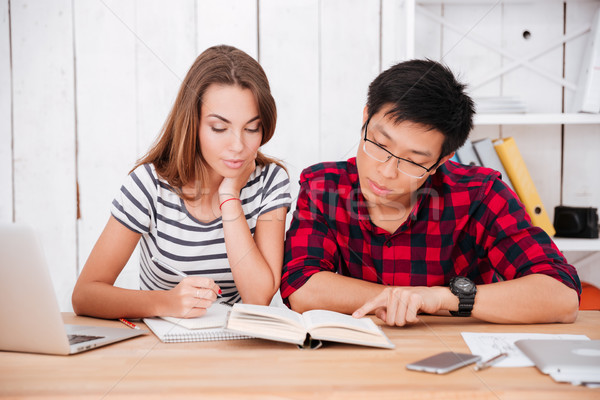 Students learning education material in classroom while looking at book Stock photo © deandrobot