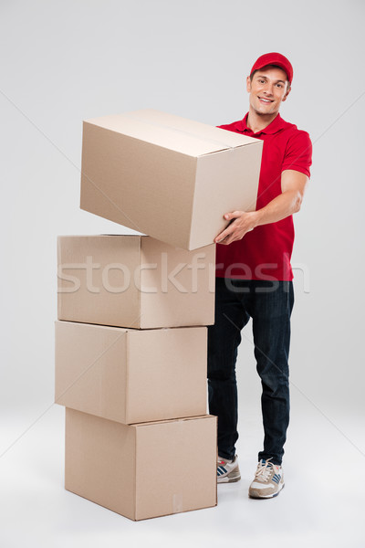 Smiling delivery man in red shirt holding big box Stock photo © deandrobot