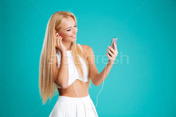 Beautiful young girl listening music with earphones and smartphone Stock photo © deandrobot