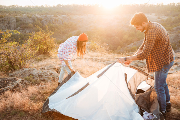 Young happy couple setting up a tent outdoors Stock photo © deandrobot