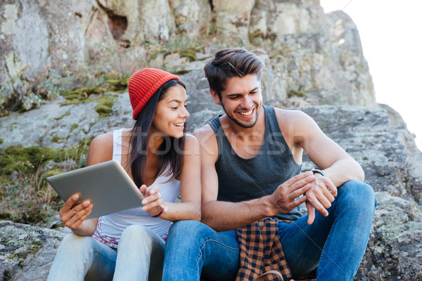 Happy young couple sitting together with tablet and using smartwatch Stock photo © deandrobot