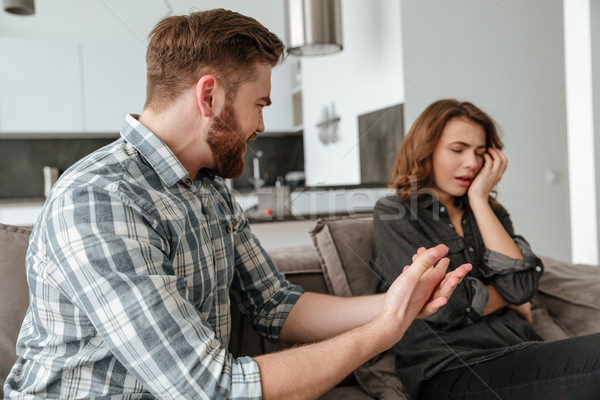 Angry young quarrel loving couple sitting on sofa indoors Stock photo © deandrobot