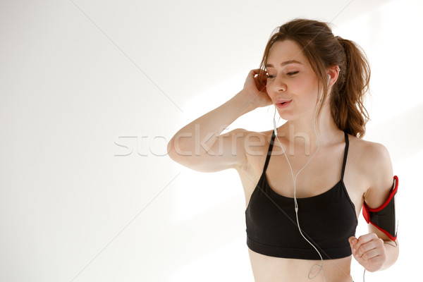 Sports woman listening music with earphones. Stock photo © deandrobot
