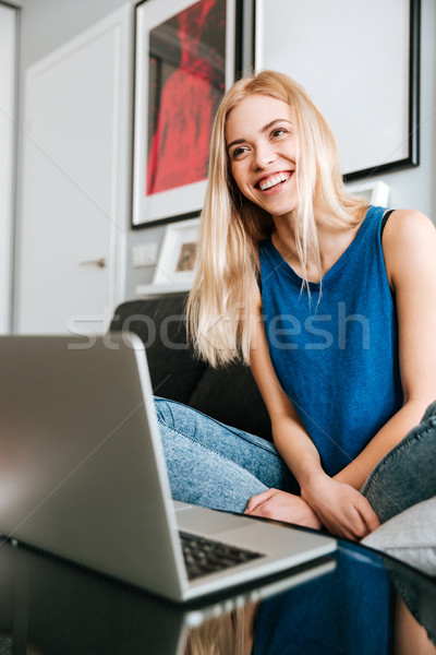 Cheerful woman sitting and using laptop at home Stock photo © deandrobot