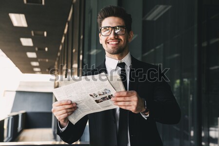 Happy young bearded businessman standing indoors Stock photo © deandrobot