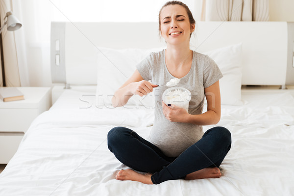 Upset pregnant woman eating ice cream on bed in bedroom Stock photo © deandrobot
