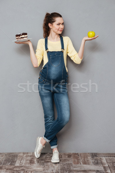 Pregnant lady choosing between sweet cake and apple. Stock photo © deandrobot