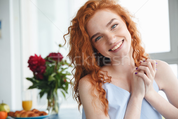 Cheerful young redhead lady sitting near flowers Stock photo © deandrobot