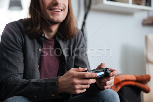 Happy young man gamer sitting at home and play games Stock photo © deandrobot