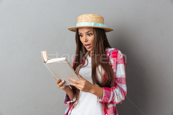 Stock photo: Close up portrait of a amazed young woman in straw hat reading a