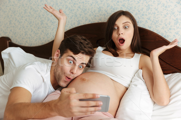 Funny happy young pregnant couple taking selfie Stock photo © deandrobot