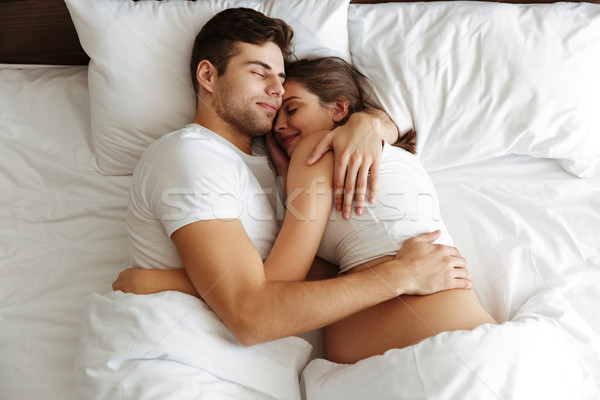 Pregnant Woman Sleeping In Bed With Her Husband Stock Photo