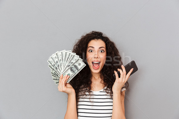 Lucky woman with curly hair holding fan of 100 dollar bills and  Stock photo © deandrobot