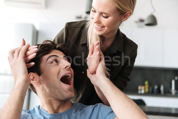 Young lady playing with her man while sitting in living room Stock photo © deandrobot