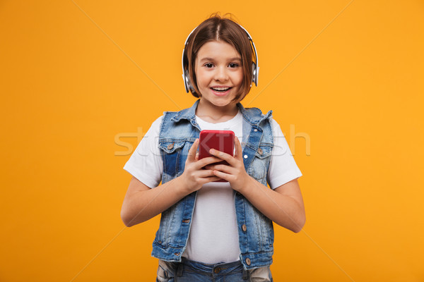 Portrait of a joyful little schoolgirl listening to music Stock photo © deandrobot