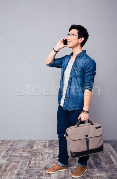 Happy youg asian man talking on the phone  Stock photo © deandrobot