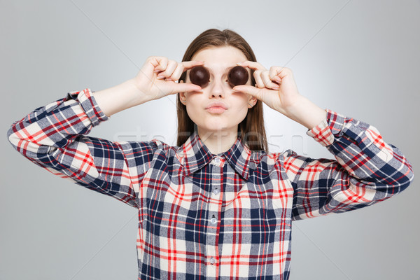 Beautiful teenage girl covered her eyes with round chocolate candies  Stock photo © deandrobot